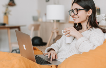 A woman in glasses relaxes with a laptop