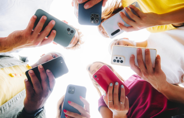 Students stand in a circle with their phones out